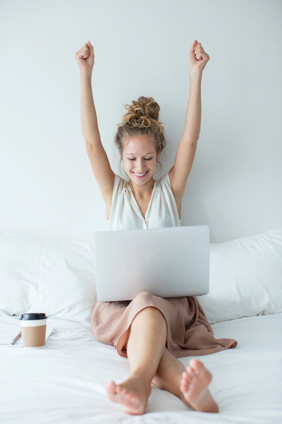 woman with arms raised and a laptop in her lap